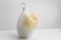Close-up of yellow washcloth on dispenser bottle against white studio background. Royalty Free Stock Photo