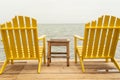 Image of 2 yellow adirondack chairs on a dock