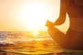 Close-up Yoga woman meditating at serene sunset or sunrise on the beach. The girl relaxes in the lotus position. Fingers Royalty Free Stock Photo