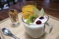 Close up of yogurt pudding in a glass with fruits decorate,honey conflake in a mug shot,orange juice in a glass on wooden plate