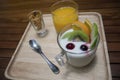 Close up of yogurt pudding in a glass with fruits decorate,honey conflake in a mug shot,orange juice in a glass on wooden plate