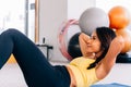 Close-up of young active and fitness Asian woman doing sit ups and crunches inside gym with exercise ball in background Royalty Free Stock Photo