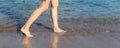 Close-up young adult beautiful slim female barefoot leg girl walking along clear water waves of sea ocean beach shore. Summertime Royalty Free Stock Photo