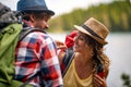 close up of young adult couple in nature, looking each other, smiling, with backpacks and hats Royalty Free Stock Photo