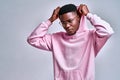 Close up of young african american man in pink streetwear hoodie with hood on head posing isolated on grey background in studio Royalty Free Stock Photo