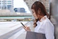 Close up young Asian employee woman using mobile phone in her hands for job at outside office.