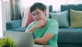 Close-up of a young Asian man in a green shirt, sitting at a laptop screen, with a serious look on his face and a thoughtful Royalty Free Stock Photo