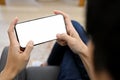 Close-up, A young Asian man relaxing in living room and playing mobile game on his smartphone Royalty Free Stock Photo