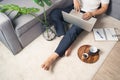 Close up of young Asian man sitting on floor working from home using laptop computer and notebook. Work from home concept Royalty Free Stock Photo