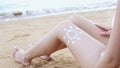 Close up young asian woman applying a sunscreen or sunblock lotion on leg her skin on a seaside beach tropical resting and relaxat Royalty Free Stock Photo