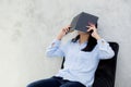 Close up of young asian woman reading book and hiding face on cement background Royalty Free Stock Photo