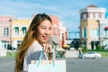 Close up of a young Asian woman shopping an outdoor flea market with a background of pastel bulidings and blue sky. Royalty Free Stock Photo