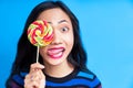 Close up of young asian woman sticking out tongue covering her eye with colorful lollipop Royalty Free Stock Photo