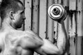 Close up young athletic man doing workout with heavy dumbbell against the background of agray metal wall Royalty Free Stock Photo
