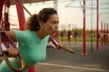 Close-up of young athletic woman with perfect body in sportswear doing push-ups with fitness suspension straps in the sportsground