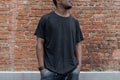 Close up of dark-skinned man in black blank T-shirt on bricked background. Royalty Free Stock Photo