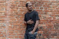 Close up of dark-skinned man in black blank T-shirt on bricked background. Royalty Free Stock Photo