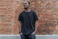 Close up of dark-skinned man in black blank T-shirt on bricked background. Royalty Free Stock Photo