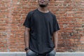 Young attractive dark-skinned man in black T-shirt on red bricked background. Royalty Free Stock Photo