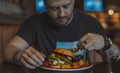 Close up of young attractive man eating burger and french fries at cafe. Royalty Free Stock Photo