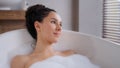 Close-up young attractive relaxed woman lying in hot foam bath with eyes closed resting relaxing in bathroom happy
