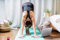 Close up Young attractive sporty woman practicing yoga, standing Downward Facing Dog pose, working out at home in living room. Royalty Free Stock Photo