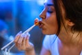 Close up of young attractive woman eating asian food with chopsticks at cafe. Royalty Free Stock Photo