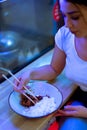 Close up of young attractive woman eating asian food with chopsticks at cafe. Royalty Free Stock Photo