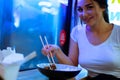 Close up of young attractive woman eating asian food with chopsticks at cafe. Royalty Free Stock Photo