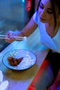 Close up of young attractive woman eating asian food with chopsticks at cafe. Royalty Free Stock Photo