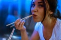 Close up of young attractive woman eating asian food with chopsticks at cafe. Royalty Free Stock Photo