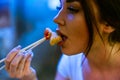 Close up of young attractive woman eating asian food with chopsticks at cafe. Royalty Free Stock Photo