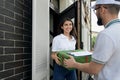 Deliveryman giving gift box and folder to woman. Royalty Free Stock Photo