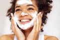 Close up of young beautiful darkskinned woman cleaning her skin with facial wash Royalty Free Stock Photo