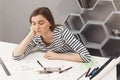 Close up of young beautiful sleepy freelance architect girl holding head with hand, falling asleep while preparing Royalty Free Stock Photo