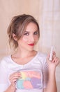 Close up of a young beautiful smiling woman holding a menstruation cotton tampon in her hand and a colorful purse inn Royalty Free Stock Photo