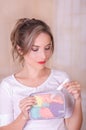 Close up of a young beautiful smiling woman holding a menstruation cotton tampon in her hand and a colorful purse in her Royalty Free Stock Photo