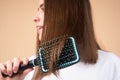 Close up young beautiful woman combing brown hair. Hair Care. Beautiful brunette woman hairbrushing hair with hairbrush Royalty Free Stock Photo