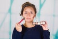 Close up of young beautiful woman holding a make up palette and doing crazy make-up in her face using a brush, in a