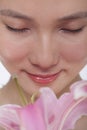 Close -Up of young beautiful woman smelling a large pink flower, studio shot Royalty Free Stock Photo