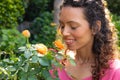 Close-up of young biracial woman smiling while smelling flower with eyes closed in garden Royalty Free Stock Photo