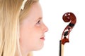 Close up of young blonde girl looking at the head of a violin on a white studio background Royalty Free Stock Photo