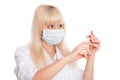 Close-up of a young blonde nurse in a mask looking at a syringe Royalty Free Stock Photo