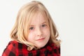 Close up of a young blonde preteen girl with neutral expression on a white studio background