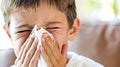 Close up of young boy with a cold blowing his nose into tissue for relief from illness Royalty Free Stock Photo