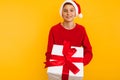 Close-up of a young boy in a red sweatshirt with a gift and a santa claus hat. holding a Christmas present Royalty Free Stock Photo