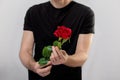 Close up of young brutal man holding red rose. studio shot