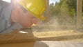 CLOSE UP: Young builder blows a layer of sawdust off a plank lying on workbench. Royalty Free Stock Photo