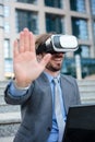 Close up of a young businessman using VR goggles in front of an office building. Selective focus concept, focus on head Royalty Free Stock Photo