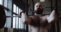 Close-up young Caucasian athlete man lifting heavy barbell in large hardcore gym hall. Ambition and challenge concept. Royalty Free Stock Photo